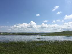 grass water blue clouds