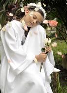 Girl in the white clothing and with pink rose flower on First Communion