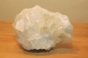 Close-up of the beautiful and colorful, shiny rock crystal, with the shadow, on the wooden surface