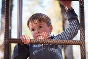Boy climbing up the metal ladder at blurred background