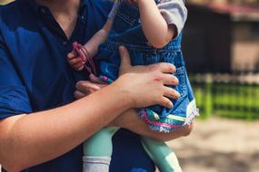Father holds baby daughter at breast, detail