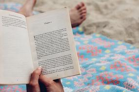 book in the hands of a girl lying on the bed