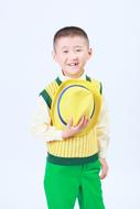 Handsome asian child boy holding hat at chest