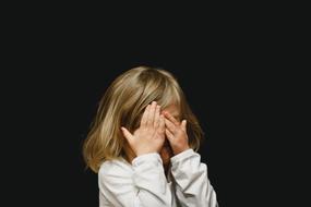 child covers his face with hands