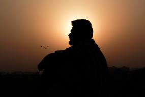Silhouette of Sitting man at sunset sky