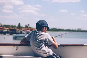 boy catches fish sitting in a boat