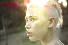 Portrait of a blonde girl with tattoo, in sunlight on the head