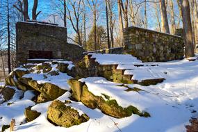 Beautiful and colorful, old, stone structure in white snow, in light, among the colorful trees