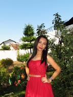 young woman in red dress posing in garden