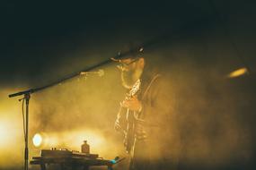 musician with a beard and glasses on stage in the haze