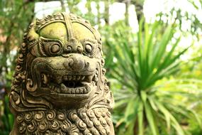 lion stone sculpture in leaves