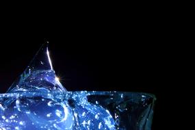 Close-up of the beautiful, blue liquid in the glass, with the bubbles, in light, at black background