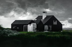 black cottage on a background of gray rainy sky