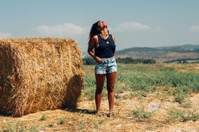 photo of a tanned girl by a haystack