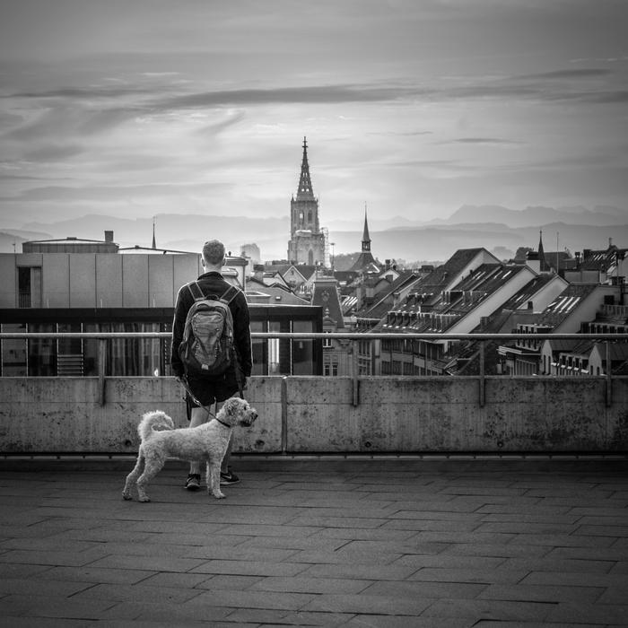 Black and white photo with the man with dog on the beautiful cityscape of Bern, Switzerland