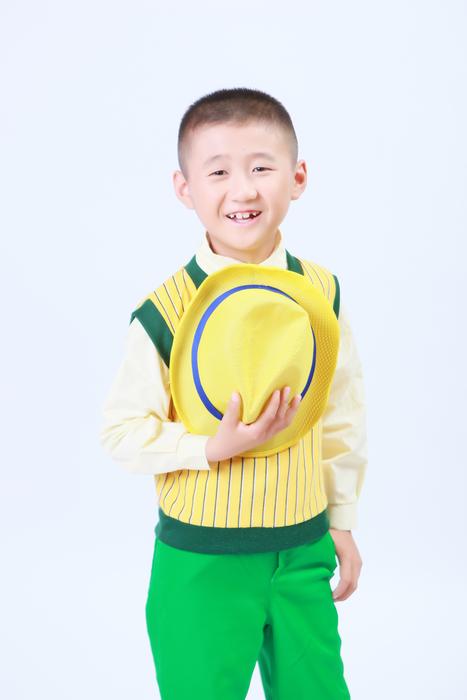 Handsome asian child boy holding hat at chest