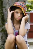 serious child Girl in colorful hat sits outdoor