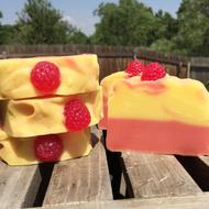 Beautiful and colorful cake like handmade soap with the berries, on the wooden surface, among the green trees