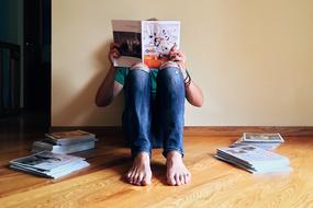 young man reads magazines while sitting on the floor