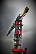 Colorful, industrial crane, under the black and white sky with clouds