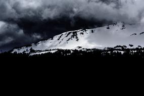 black and white, thick clouds over a snowy mountain
