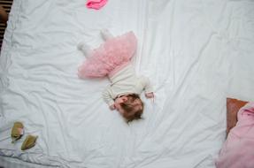 Baby girl sleeps on white blanket, flat lay