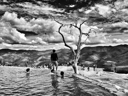 people in a natural pool in the mountains in black and white background