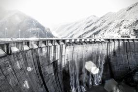 Black and white photo of the water dam, among the mountains, in light