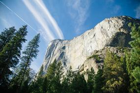 Blue Sky with cirrus Clouds over grey cliff and forest