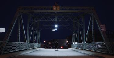 man walking on bridge in city at night