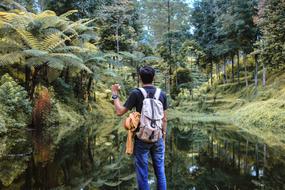 Man with a backpack near the water among the colorful plants