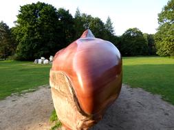Shiny, brown stone sculpture, among the beautiful, green and meadows, with the green trees