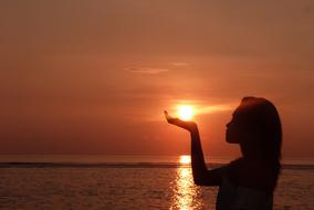 girl with the sun in her hand at sunset in bali