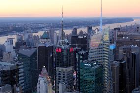 Beautiful cityscape of the shiny buildings in New York and river, USA, at colorful sunset in the sky