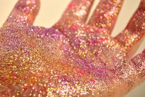 hand covered with colorful glitters