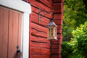 Lantern, on the beautiful, red, wooden cottage with the door, among the colorful trees