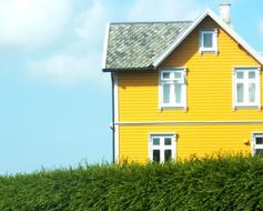 Yellow and white house, on the green grass, under the blue sky with white clouds, clipart