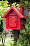 Red mail box among the green plants near the house