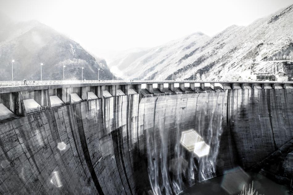Black and white photo of the water dam, among the mountains, in light