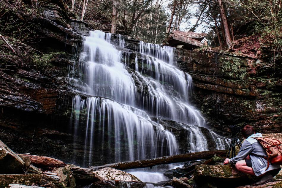 man with a camera near the waterfall