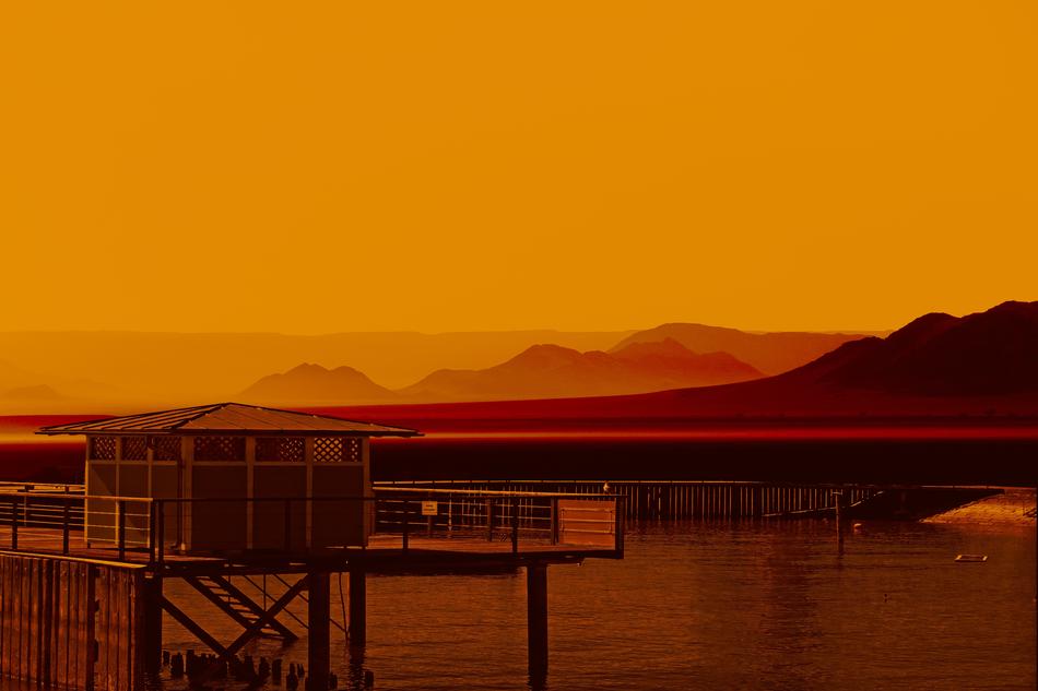 hut on pier at idyllic Sunrise, orange Background