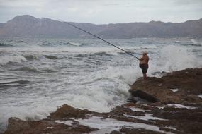 man fishing in the sea during a storm