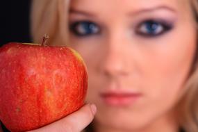 blonde holds a red apple in her hand