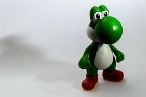 Toy of the green, white dinosaur with red feet on the white surface