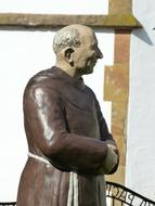 stone sculpture of a monk on the background of the monastery