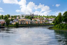 Beautiful Trondheim with the colorful buildings, and green trees in Norway, under the blue sky with clouds
