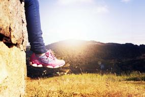 dangling foot of a man against the background of the sun