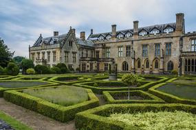 Beautiful, old abbey with the beautiful, green and yellow garden, under the blue sky with clouds