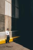 Man, standing near the colorful wall, in light, near the shadow