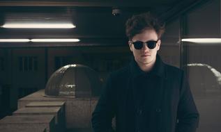 Portrait of the man with black sunglasses and in black clothing, among the lights